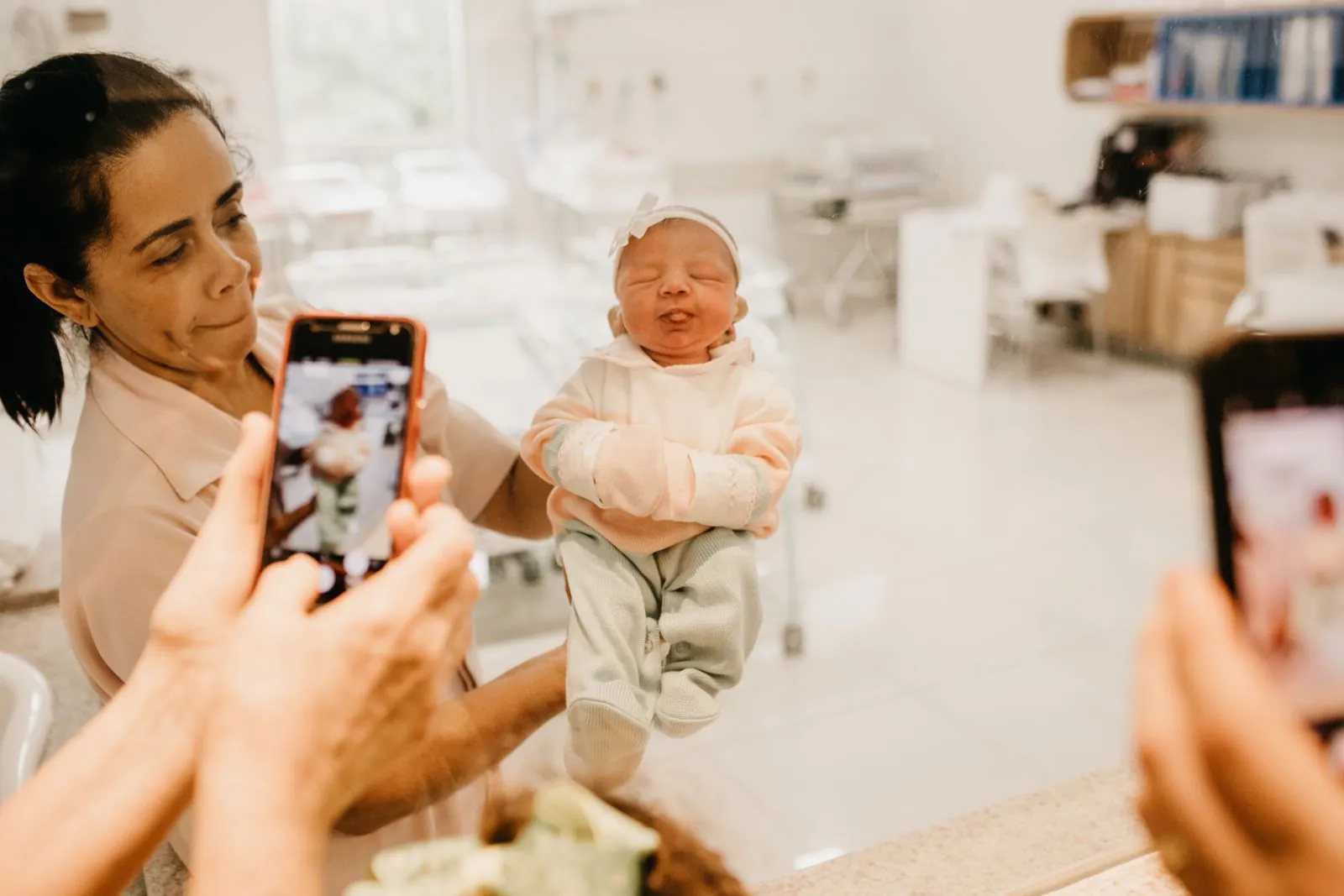 Nurse holding a newborn baby while family takes a photo in a hospital