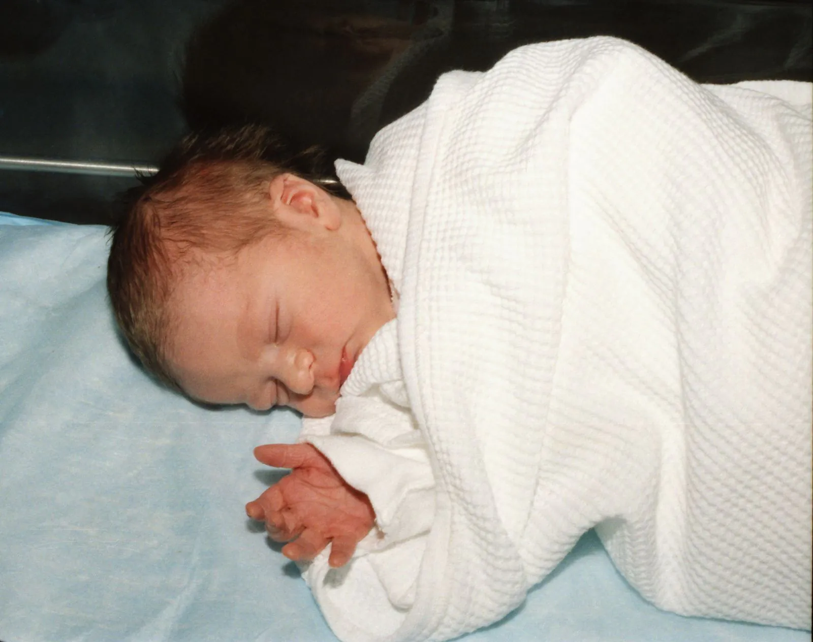 Newborn baby sleeping wrapped in a white hospital blanket