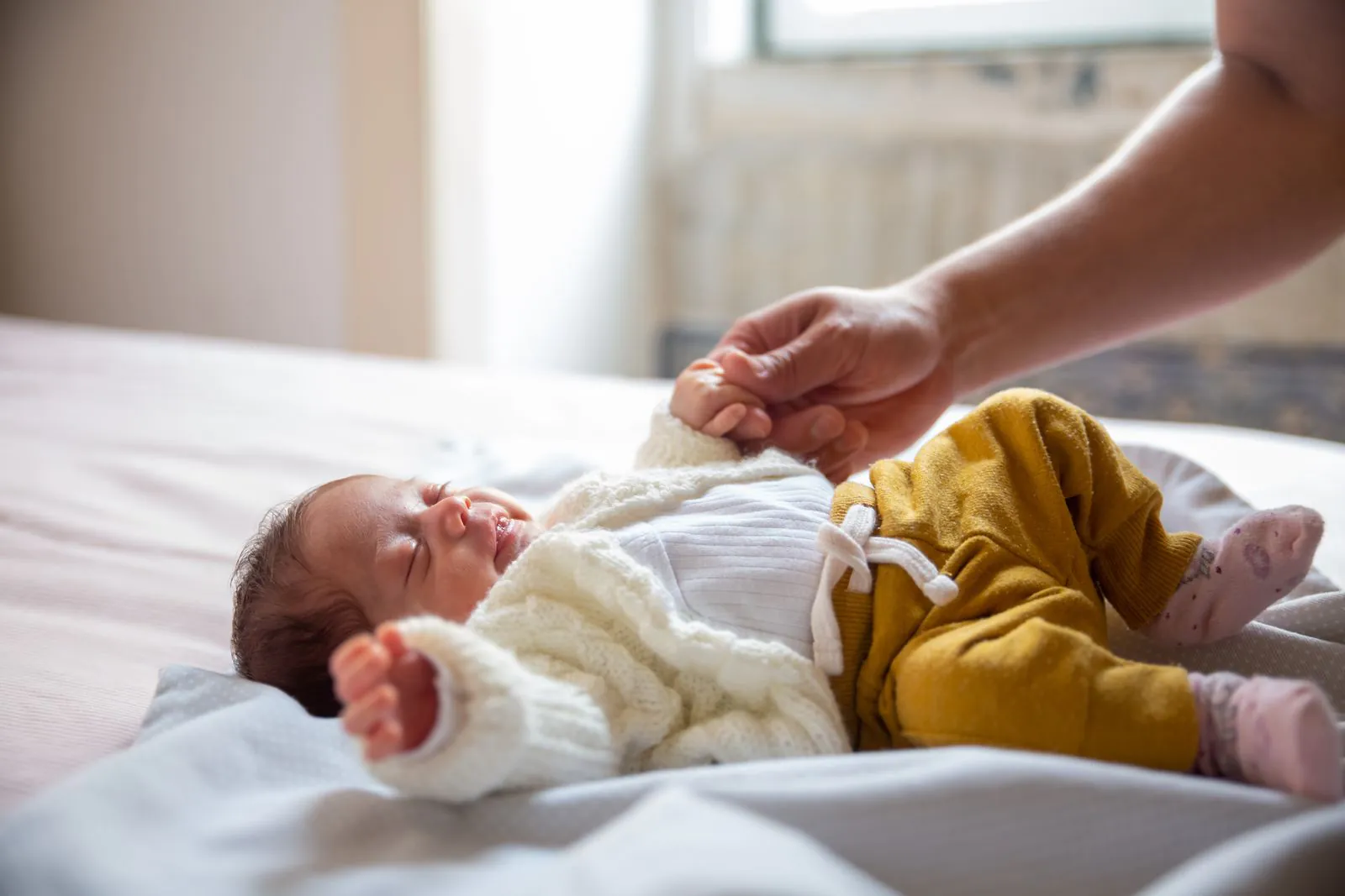 Sleeping newborn baby holding a parent's hand