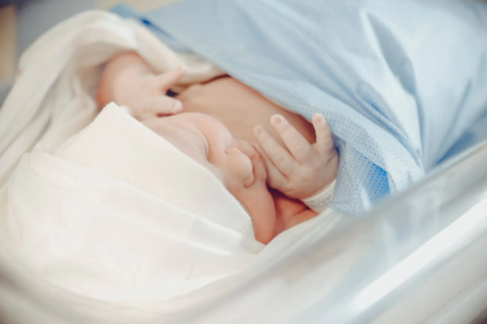 Newborn baby sleeping in a hospital wrapped in a blue blanket