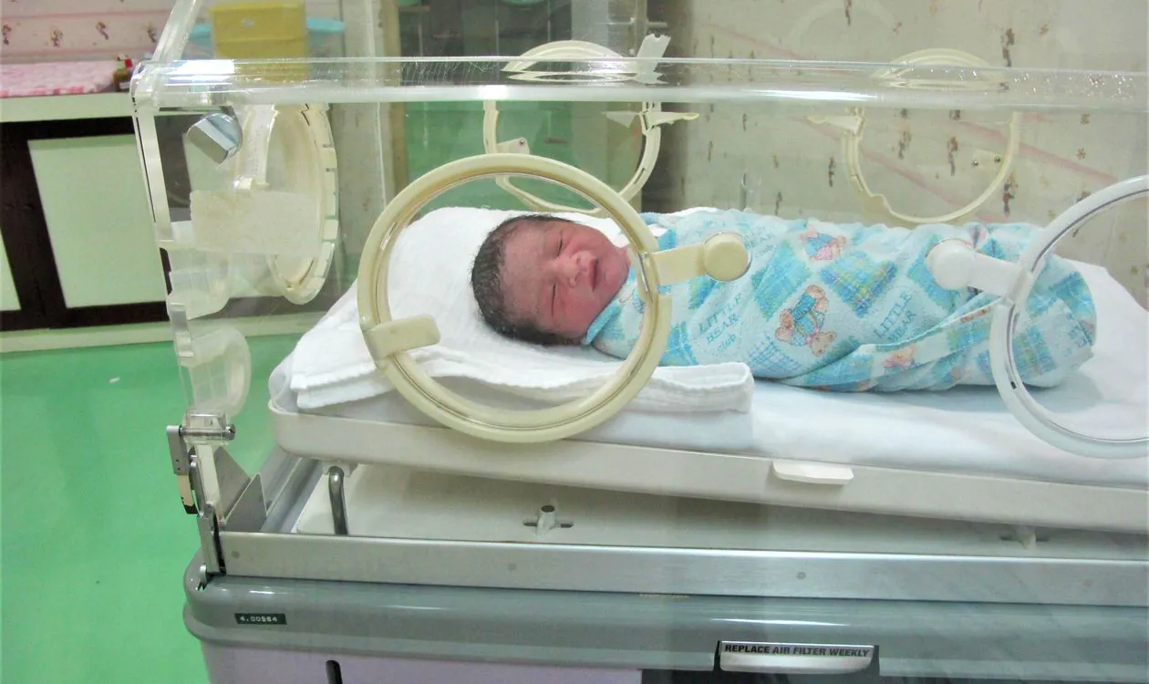Newborn baby resting in a neonatal intensive care incubator